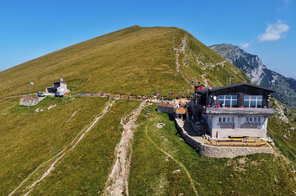 een groep mensen die op een heuvel staan met een gebouw bij Rifugio Chierego - 1911m in Brenzone sul Garda