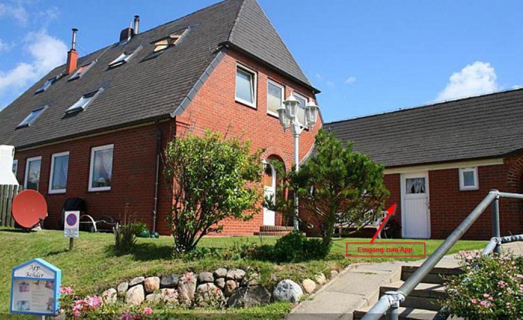 a red brick house with a landscaping in front of it at Appartement Rehder in Hörnum