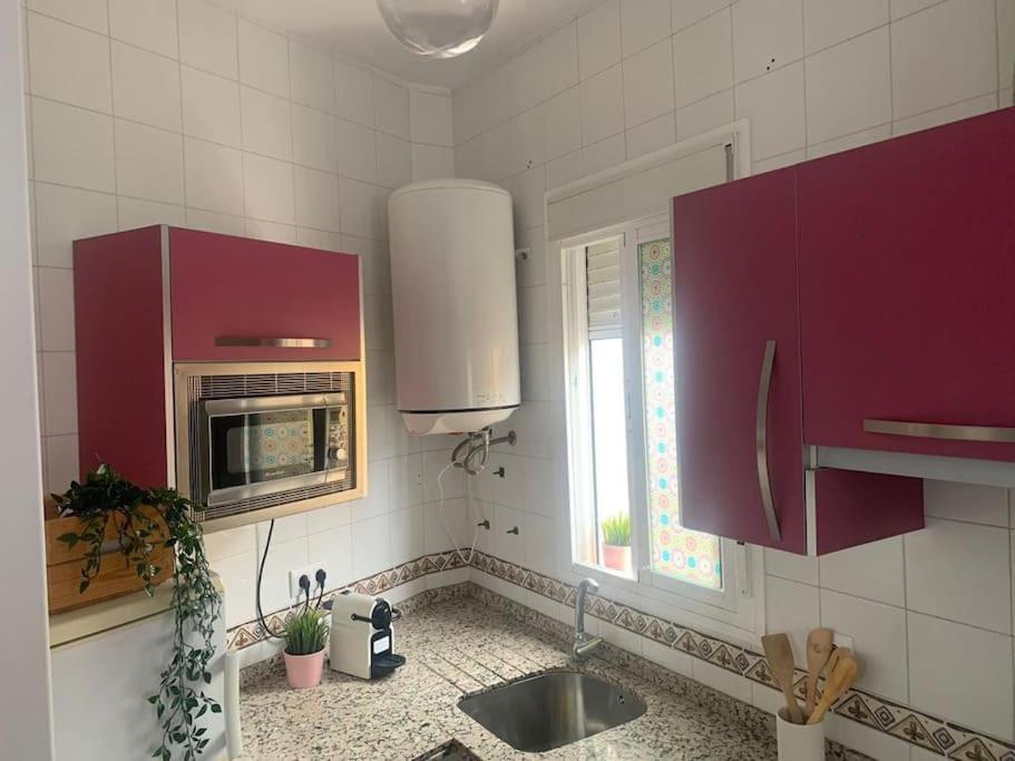 eine Küche mit lila Schränken, einem Waschbecken und einem Fenster in der Unterkunft Apartamento luminoso en Espartinas Totalmente climatizado in Espartinas
