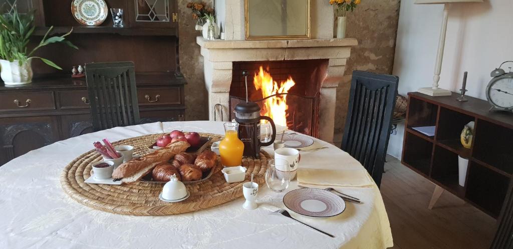 a table with a plate of food and a fireplace at Maison chaleureuse et familiale. in Nalliers
