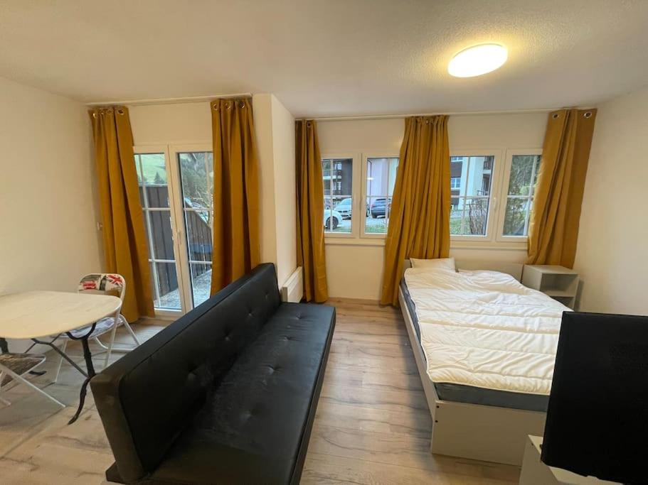 1 dormitorio con cama, mesa y ventanas en Joli studio au pied du Moleson, en Gruyères