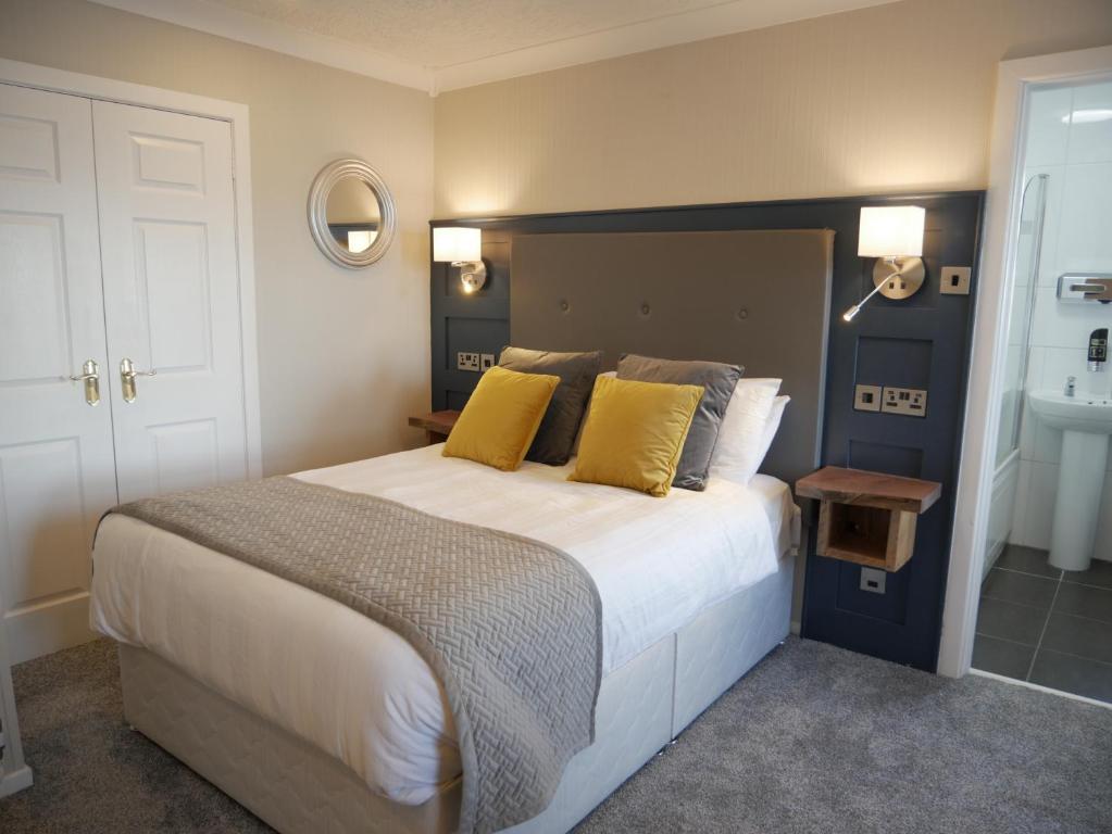 - une chambre avec un grand lit et des oreillers jaunes dans l'établissement Harbour House Inn Newcastle, Northern Ireland, à Newcastle