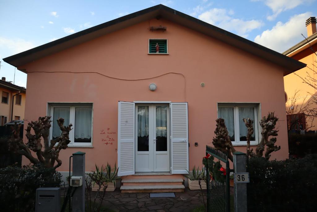 a small pink house with a white door at La Casina di Zia Zita in Pieve a Nievole