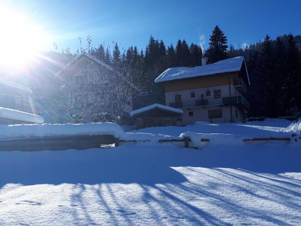 Una casa en la nieve con el sol detrás. en Pension Mitterer, en Weissensee