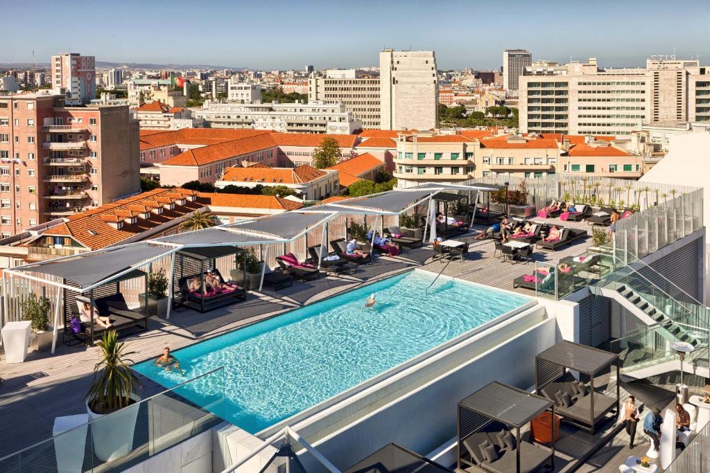 A rooftop swimming pool with loungers, cabanas and a broad city panorama.