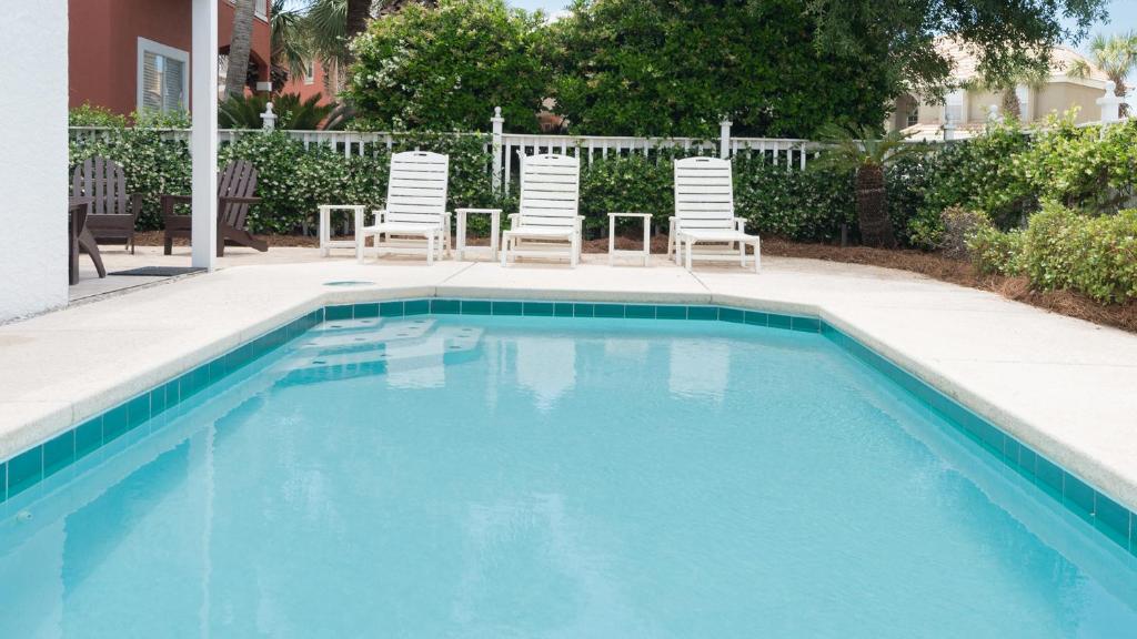 a swimming pool with two lawn chairs and a table and chairs at Dolphin House in Santa Rosa Beach