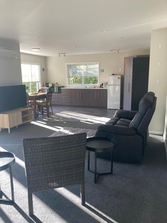 a living room with a couch and a table and a kitchen at Private Guest House in Mapua