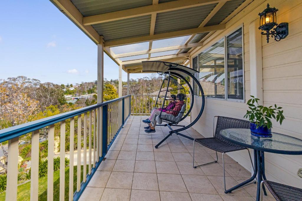 um alpendre com um baloiço e uma mesa em Sunflower Cottage em Katoomba
