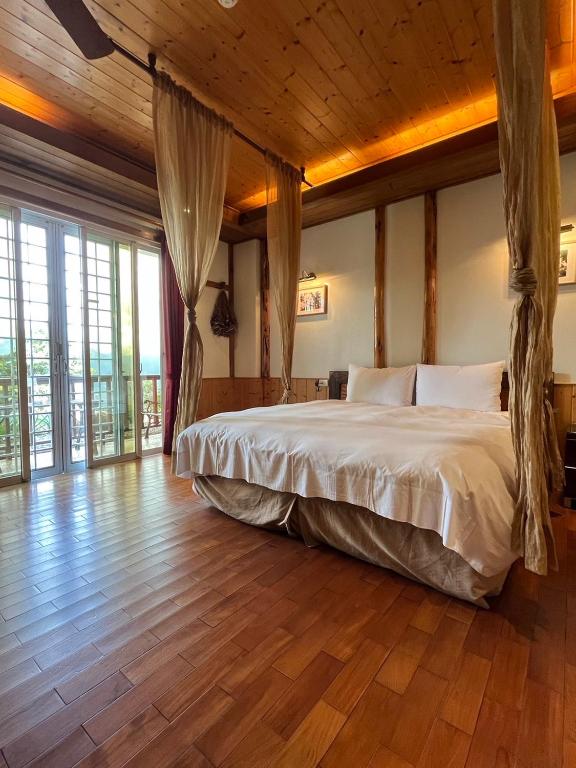 a bedroom with a large bed in a room with wooden floors at Cingjing Vienna Pleasance Cottage in Ren&#39;ai