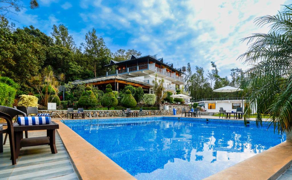 a swimming pool in front of a house at The Blossom Resort - Chikmagalur in Chikmagalūr