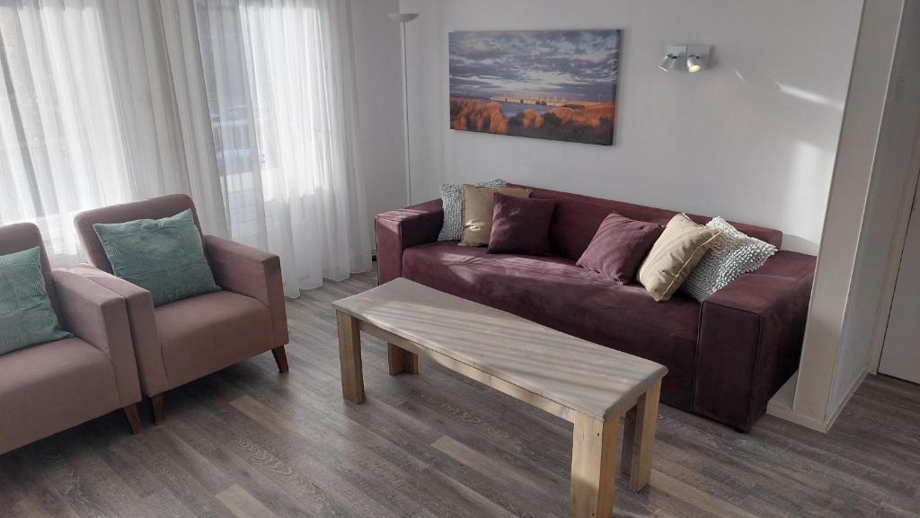 ein Wohnzimmer mit einem Sofa, 2 Stühlen und einem Tisch in der Unterkunft Appartement met 3 slaapkamers vlakbij strand en centrum in Zoutelande