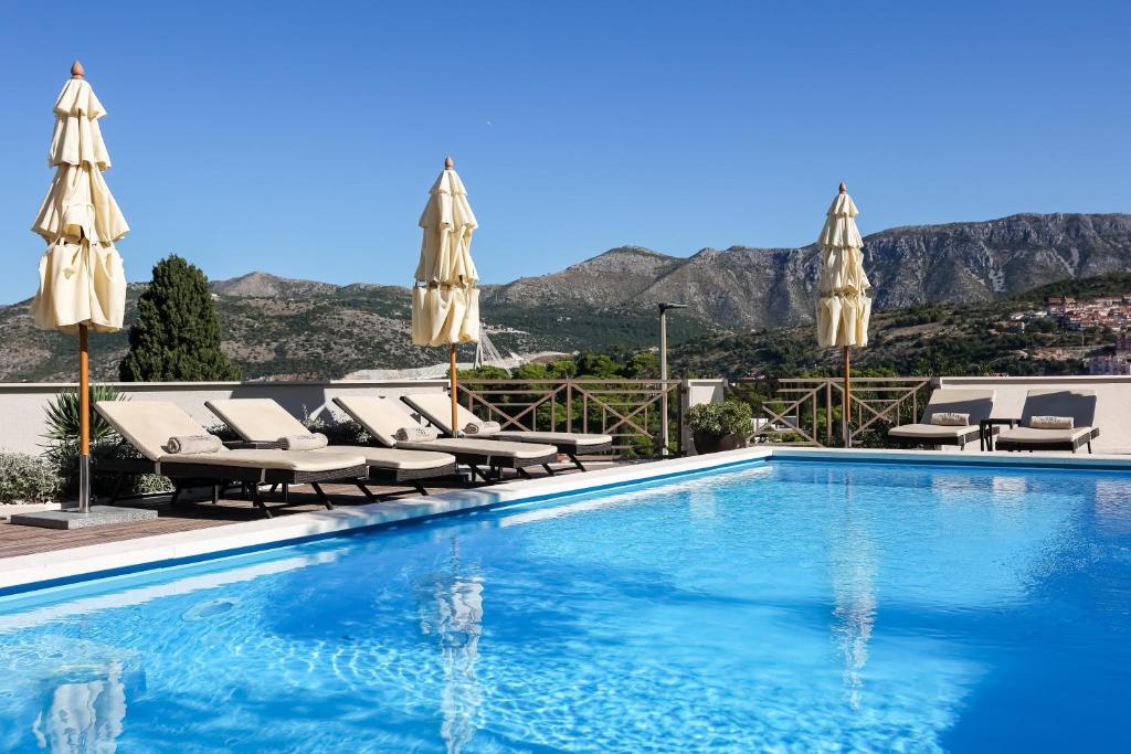 a swimming pool with chairs and umbrellas at Villa Peragro in Dubrovnik