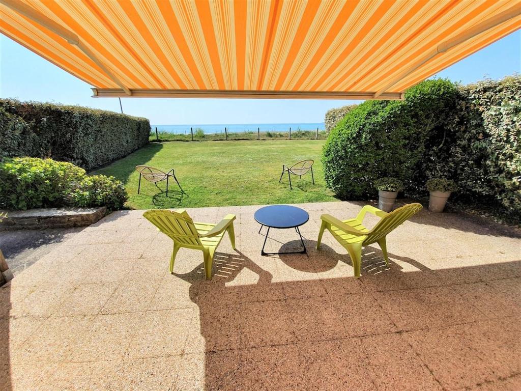 2 chaises et une table sous un parapluie orange dans l'établissement LA MER A VOS PIEDS, à La Forêt-Fouesnant