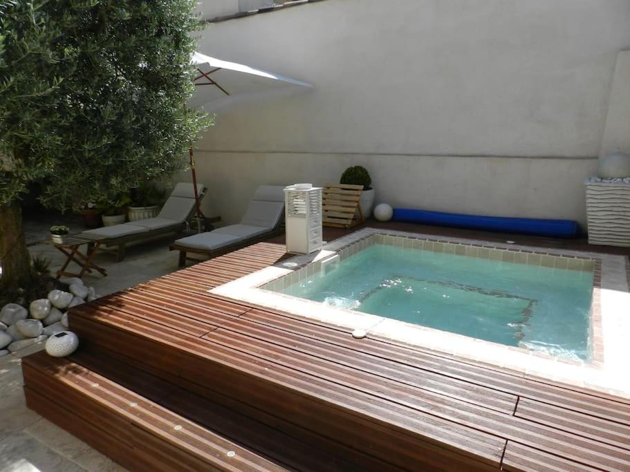 bañera de hidromasaje en una terraza junto a un patio en Le Maset des Aires avec vue sur le Luberon et son jacuzzi extérieur disponible de juin à mi-septembre, en Maubec