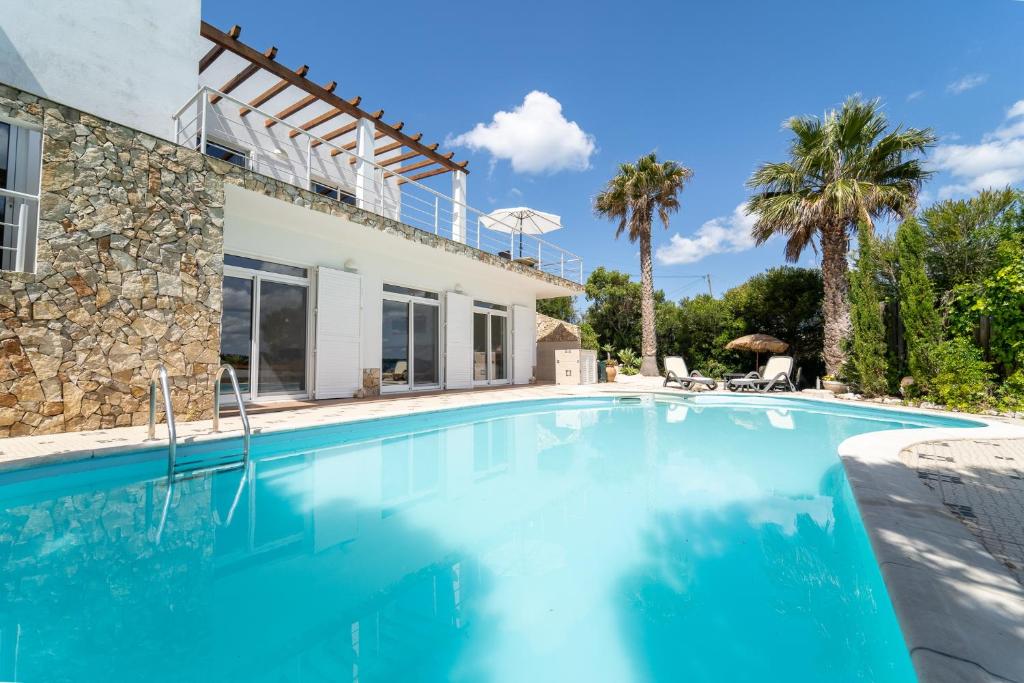 a swimming pool in front of a villa at Duas Palmeiras da Arrifana in Aljezur