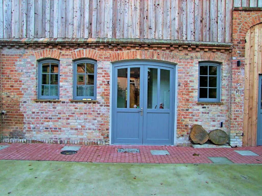 - un bâtiment en briques avec une porte et des fenêtres bleues dans l'établissement Elmenhof, à Elmenhorst