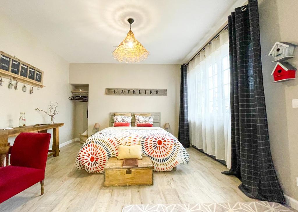 a bedroom with a bed and a red chair at Suite privative terrasse in Alençon