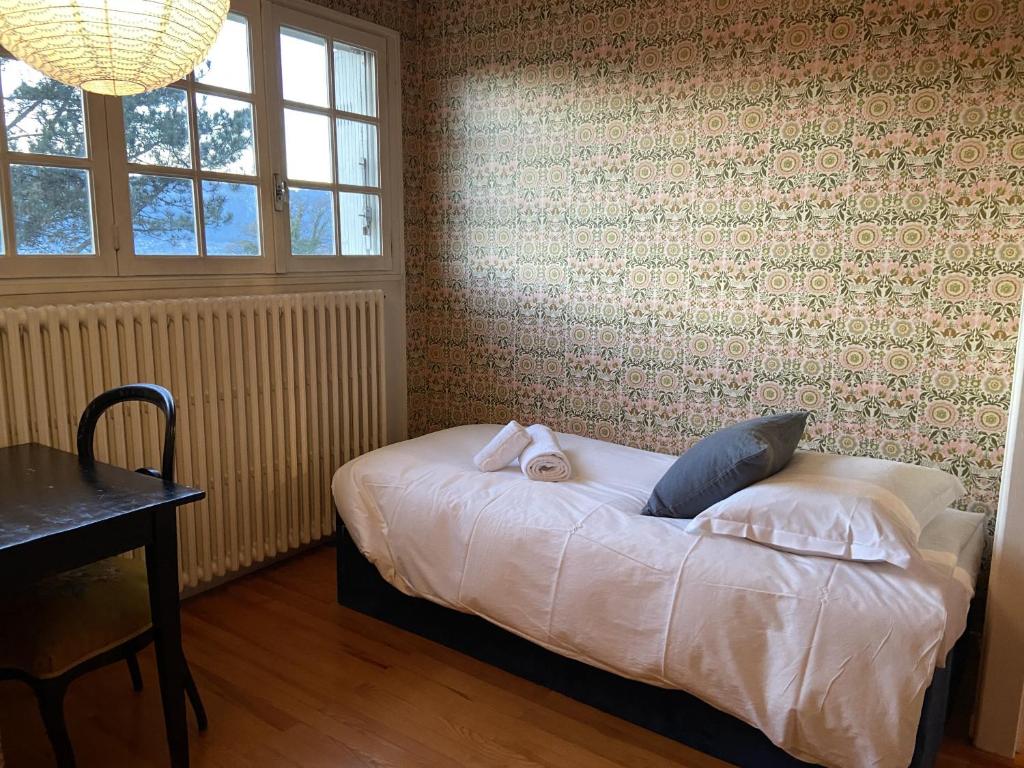 1 dormitorio con cama, mesa y ventanas en La casa du Cerisier en Veyrier-du-Lac