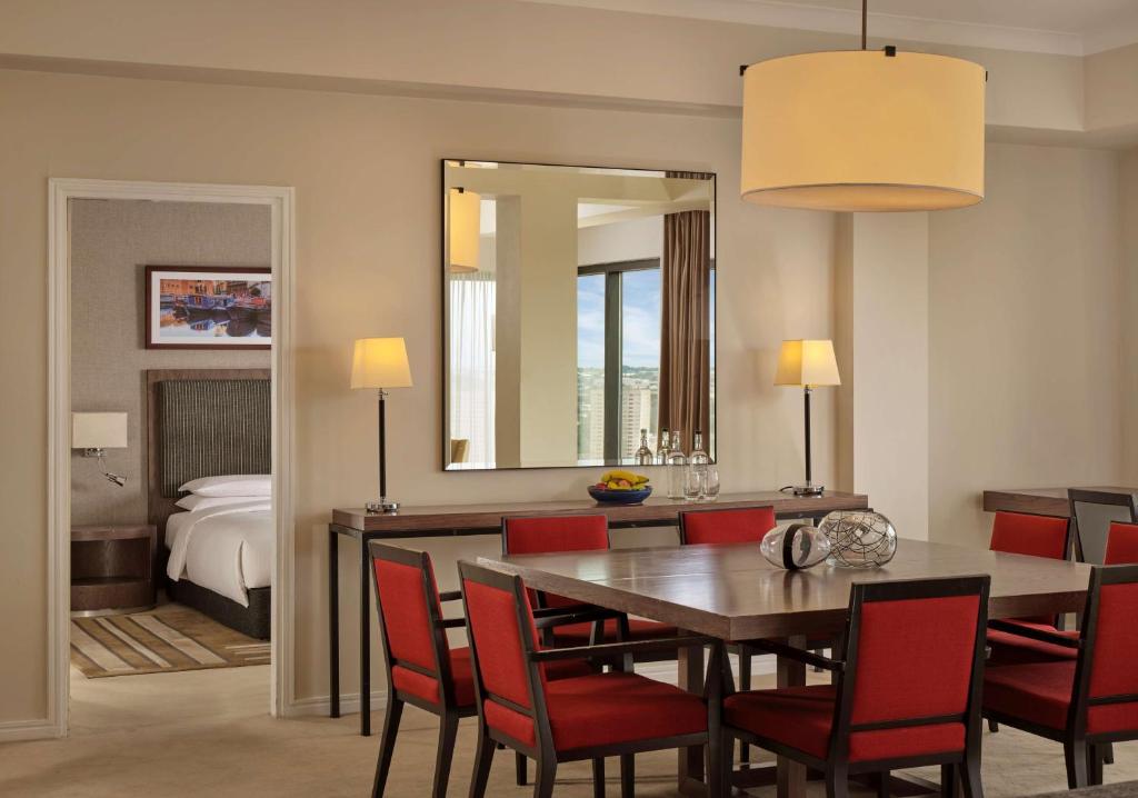 a dining room with a table and chairs and a bedroom at Hyatt Regency Birmingham in Birmingham