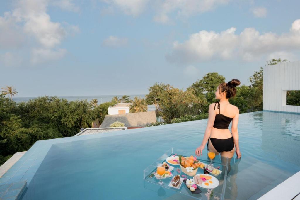 una mujer parada en una piscina con una bandeja de comida en De'sun stay pool villa, en Ban Nong Ban Kao