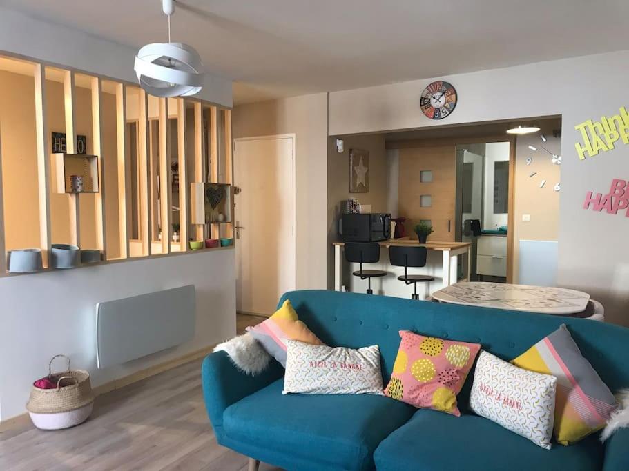 ein Wohnzimmer mit einem blauen Sofa und bunten Kissen in der Unterkunft Milly COCOON / centre ville in Milly-la-Forêt