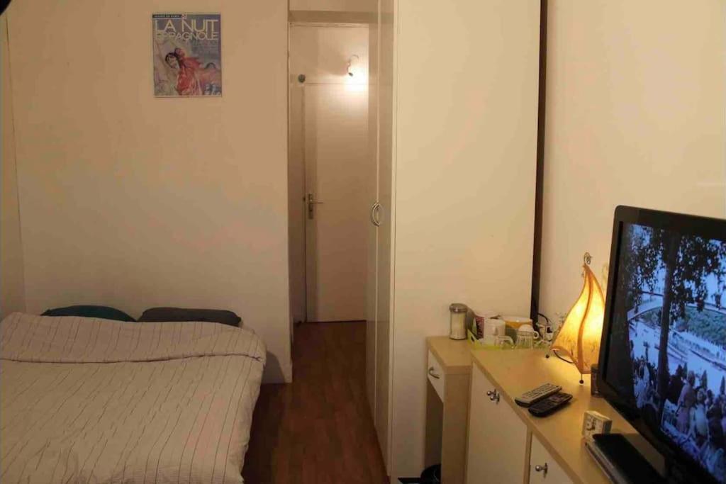 Cette petite chambre comprend un lit et une télévision. dans l'établissement Nice studio in the heart of Sceaux, à Sceaux