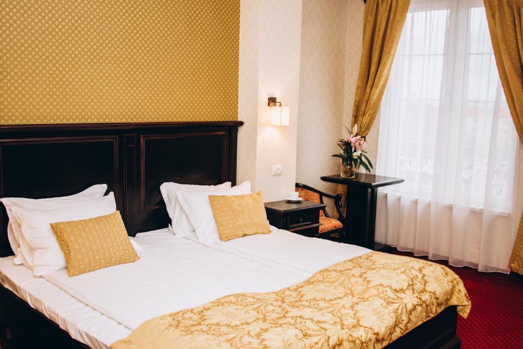 een slaapkamer met een bed met witte lakens en een raam bij Hotel Novera in Timişoara