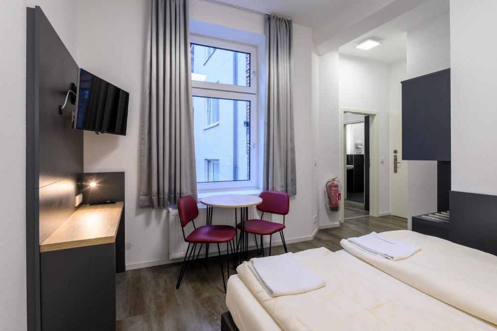 ケルンにあるRoyale Apartaments Central City Cologneのベッド、テーブル、椅子が備わるホテルルームです。