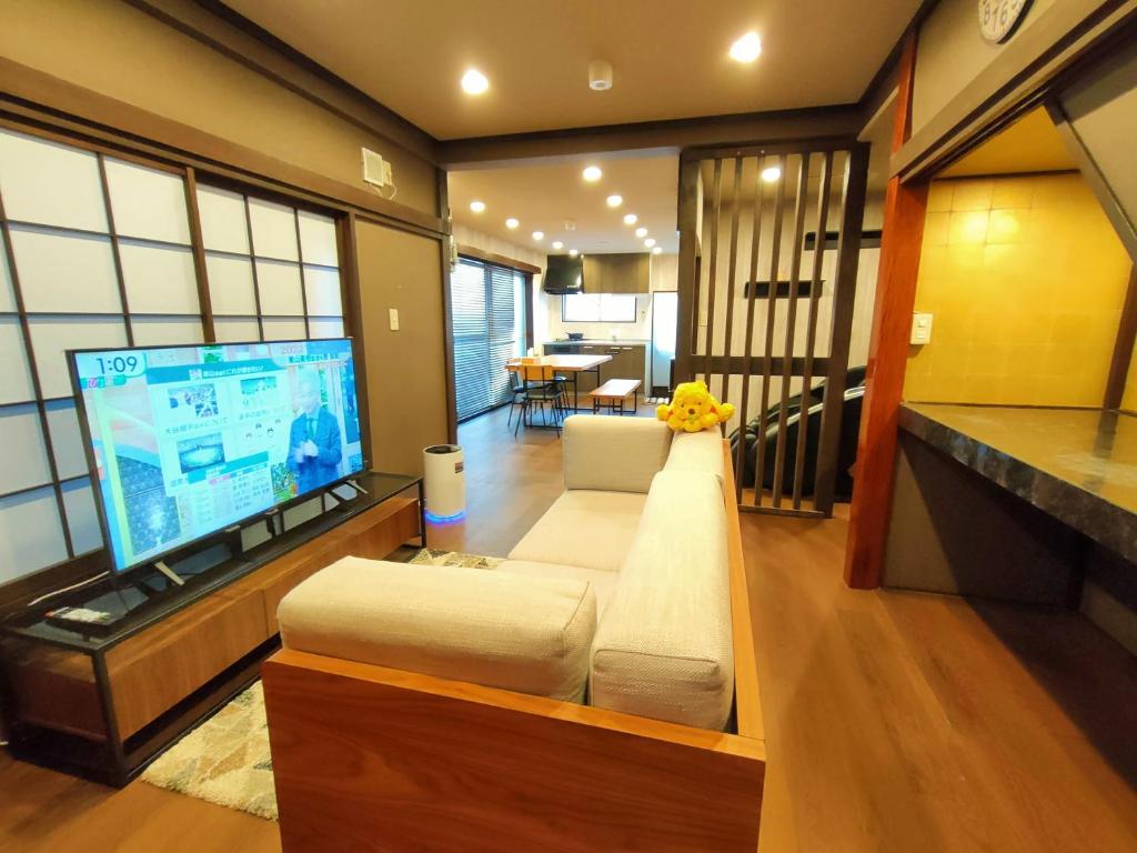 een woonkamer met een bank en een grote tv bij KIKI HOUSE in Tokyo