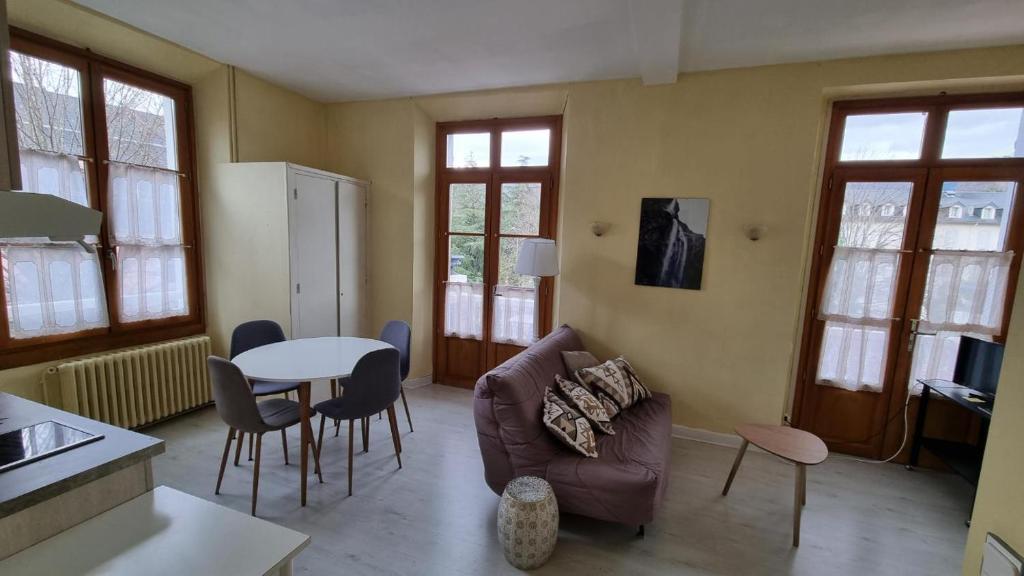 a living room with a couch and a table at T2 avec terrasse vue Hautacam dans villa historique "Victoria" in Argelès-Gazost