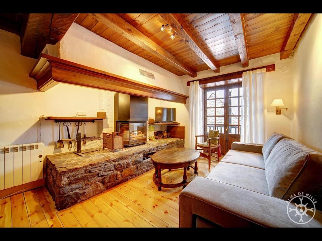 a living room with a couch and a stone fireplace at Casa Pins de Alma de Nieve in Baqueira-Beret