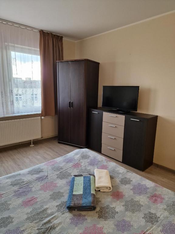 a bedroom with a bed and a dresser and a television at Centrum Noclegowe Apartament 6 in Bydgoszcz