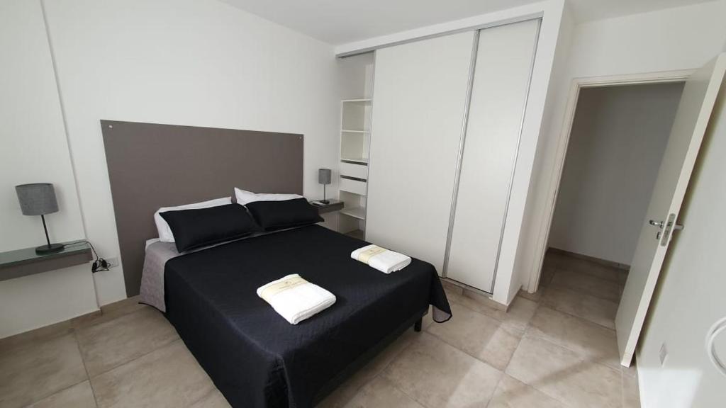 1 dormitorio con cama negra y baño en Mitre apart suite en Villa María