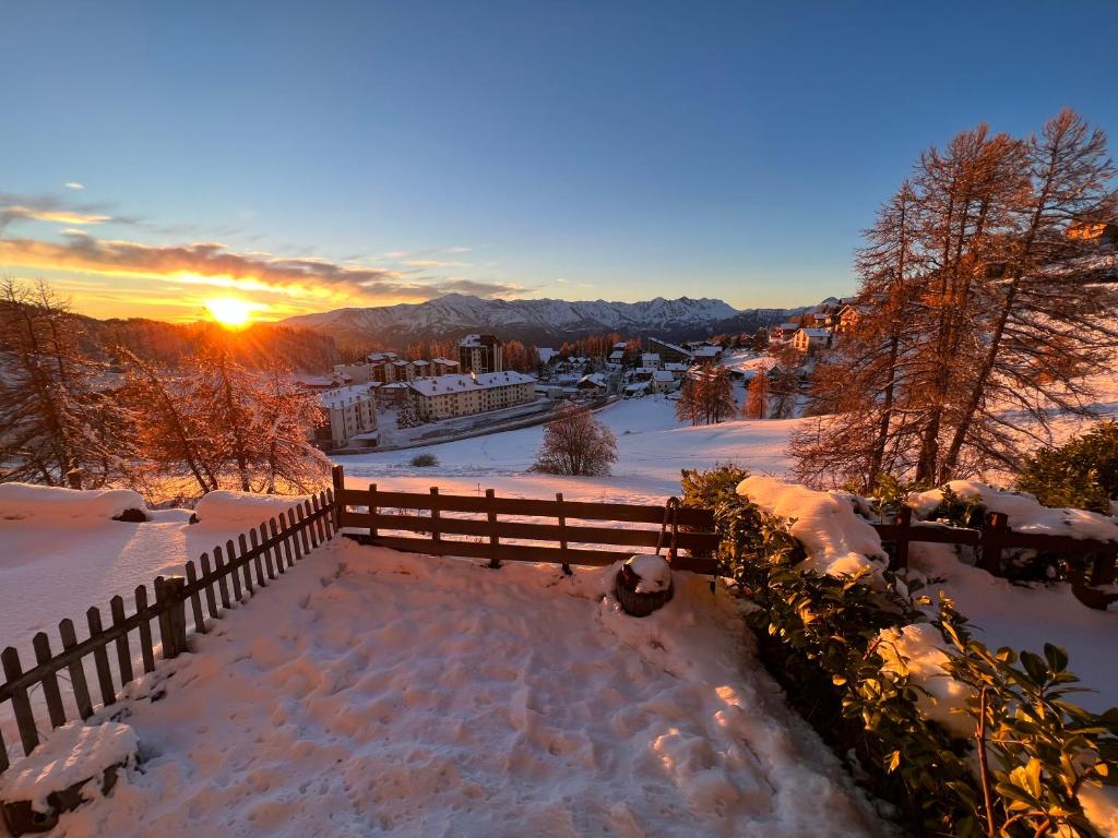 un patio cubierto de nieve con una valla y la puesta de sol en Studio avec jardin et vue imprenable sur Valberg et le Saint Honorât, en Péone