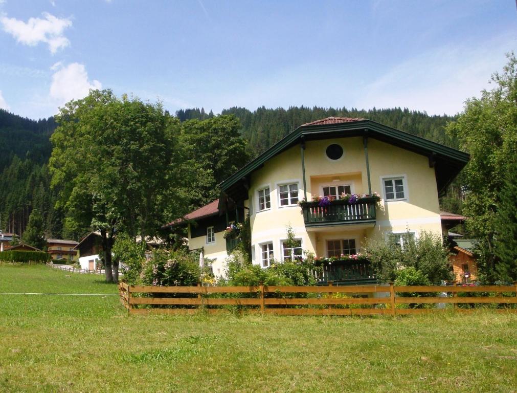 ein großes Haus mit einem Zaun auf einem Feld in der Unterkunft Apartments Geistlinger in Flachau