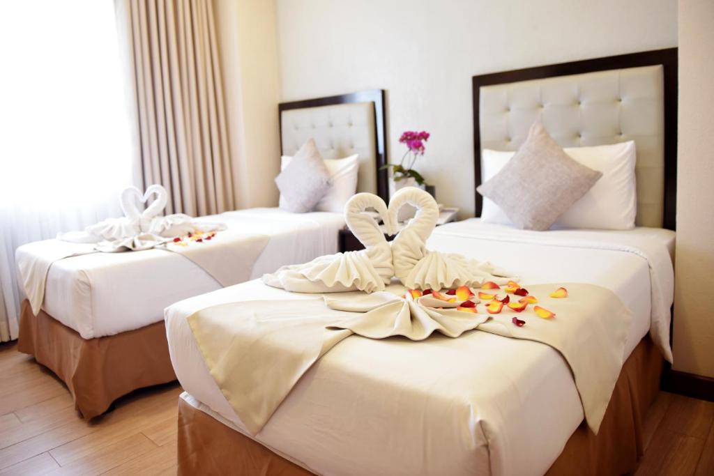 een hotelkamer met drie bedden met bloemen erop bij Aura One Hotel in Baguio