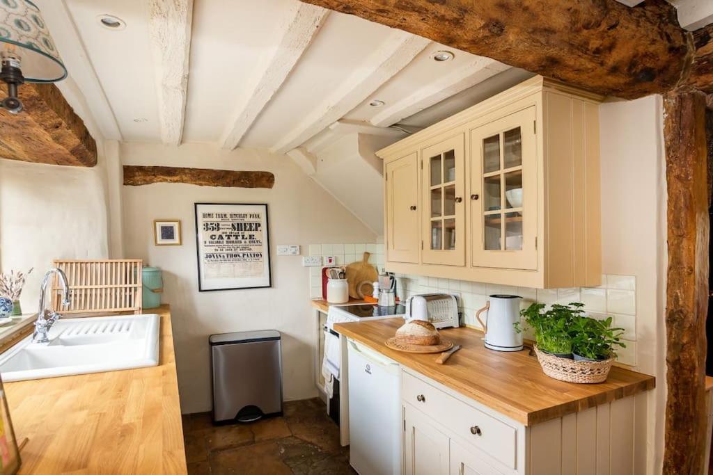 a kitchen with white cabinets and a sink at Charming 2BD Cottage in the Heart of Kingham! in Kingham
