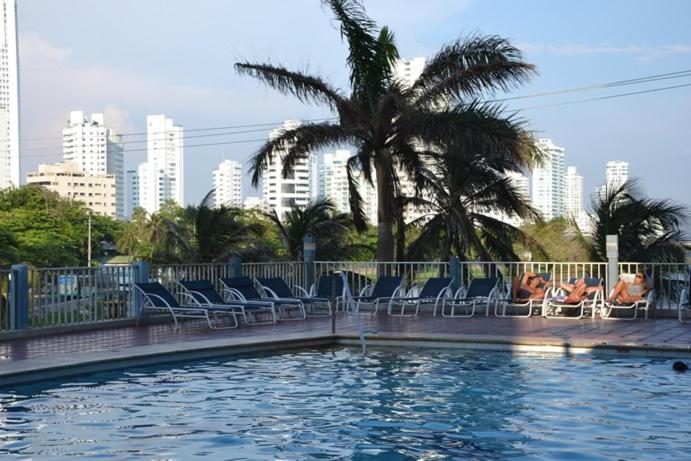 een zwembad met stoelen en een palmboom in een stad bij Apartamento 3 Carabelas Cartagena Piso 16 in Cartagena