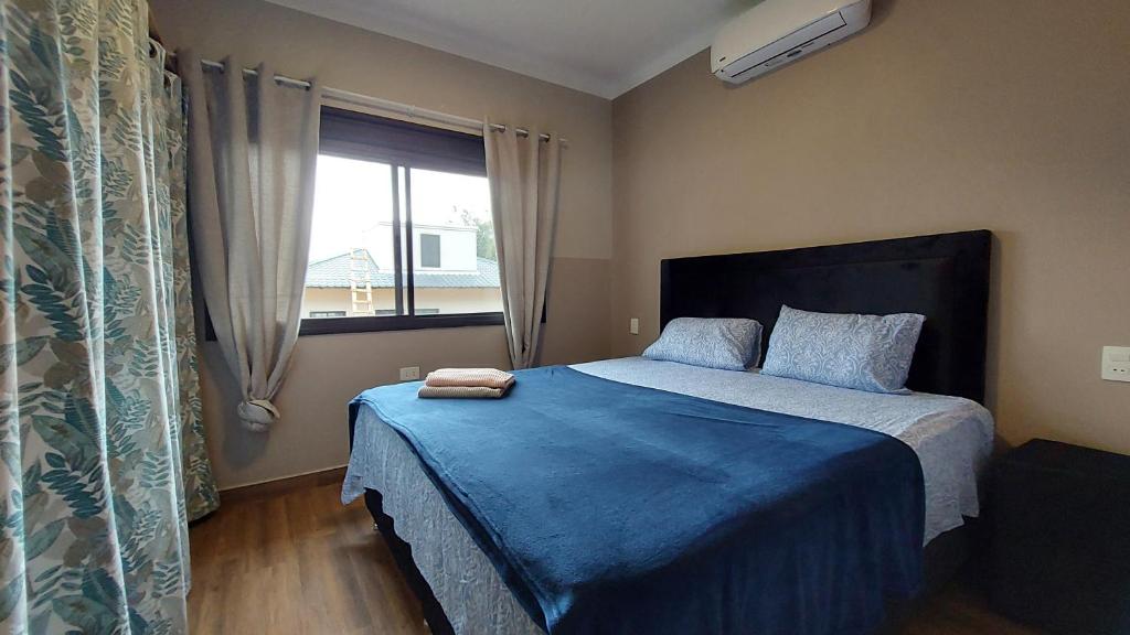 sypialnia z łóżkiem z niebieskim kocem i oknem w obiekcie Casa de huéspedes Mariposa en manantial countryclub w mieście Hohenau