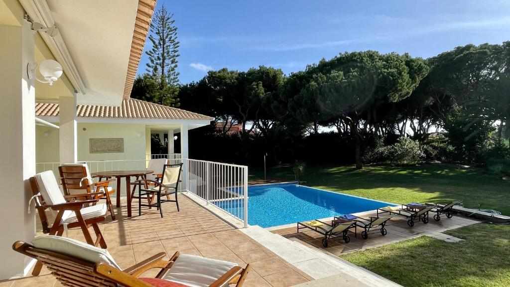 a patio with a table and chairs and a swimming pool at Azaleas - Private Pool - 12 Guests - Vilamoura in Vilamoura