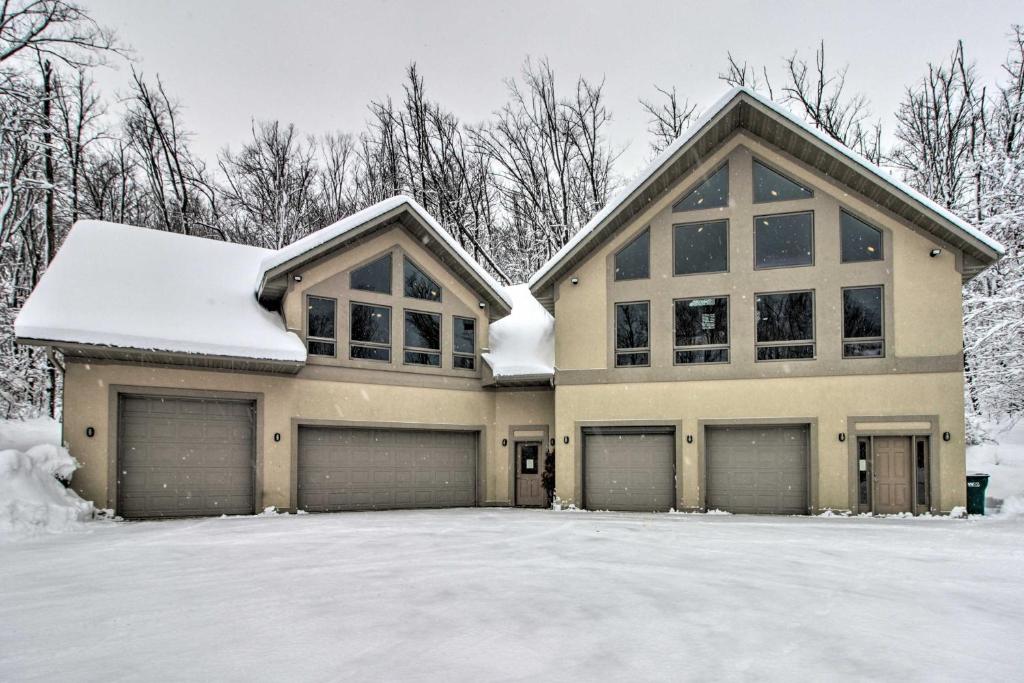 une maison avec deux portes de garage dans la neige dans l'établissement Spacious and Secluded Home by Pokegama Lake!, à Grand Rapids