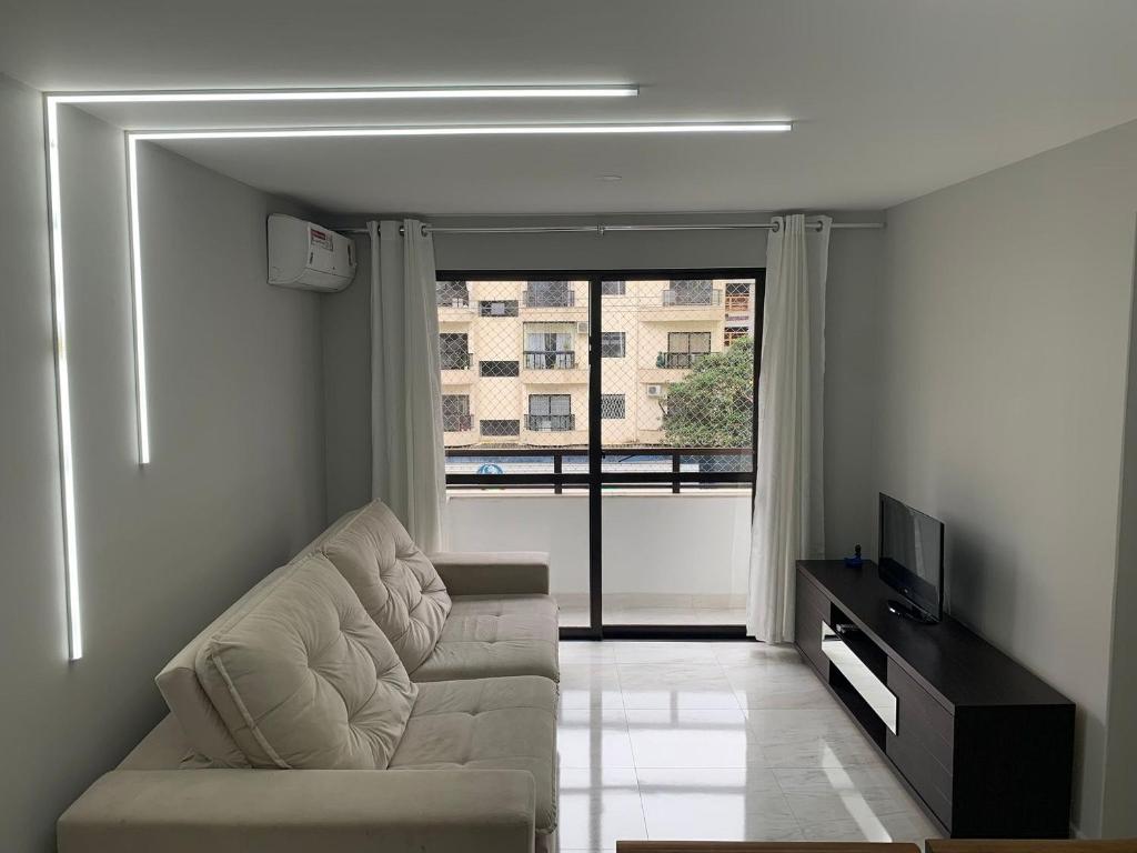 a living room with a couch and a large window at Lindo apto reformado no coração de BC in Balneário Camboriú