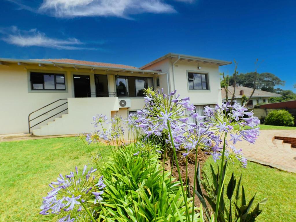 ein Haus mit lila Blumen im Hof in der Unterkunft Blue Sands Guest House in Pietermaritzburg
