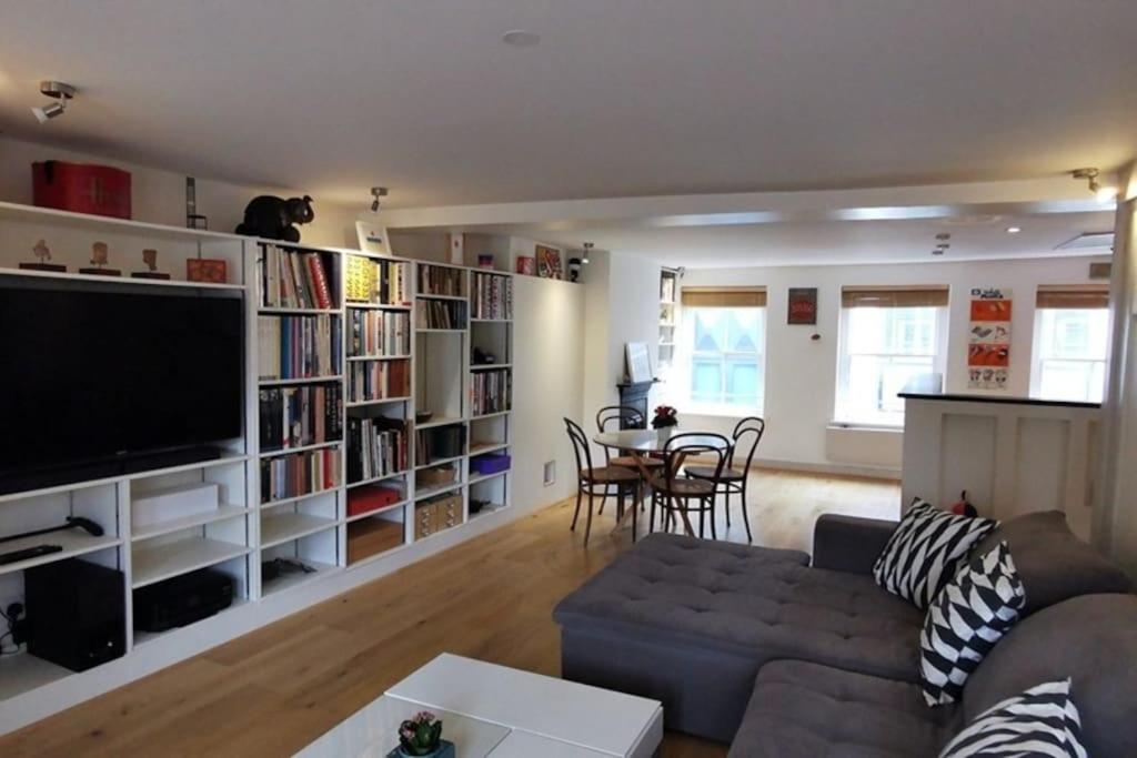 een woonkamer met een bank en een tafel met stoelen bij Spacious 2 Bedroom Apartment in the heart of Soho. in Londen