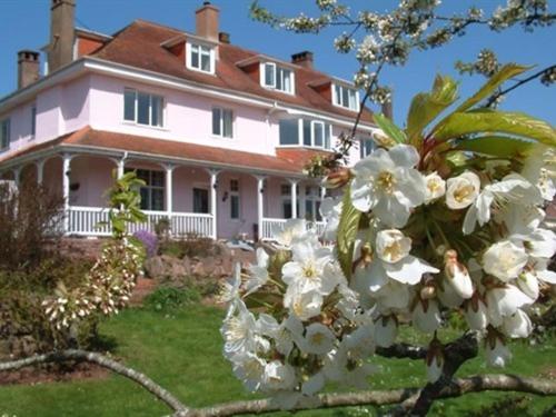 a large house with white flowers in front of it at Dunkery Beacon Country House in Wootton Courtenay
