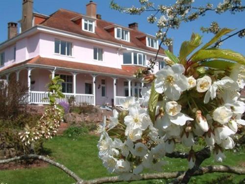duży dom z białymi kwiatami przed nim w obiekcie Dunkery Beacon Country House w mieście Wootton Courtenay