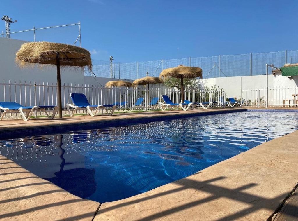 a swimming pool with chairs and umbrellas at Casa Rural Frigols in Chella