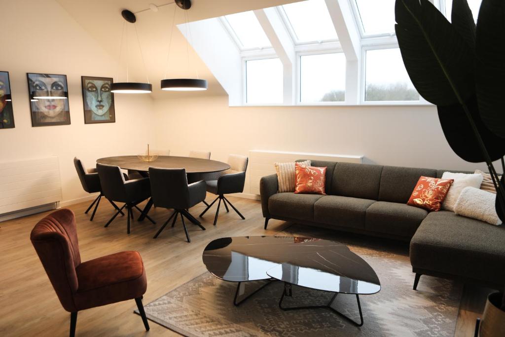 a living room with a couch and a table and chairs at Luxe en comfortabel appartement aan het water in Kamperland