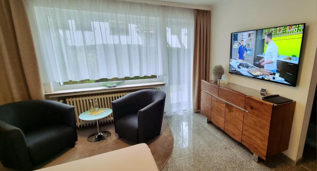 a living room with two chairs and a flat screen tv at Bonsai-Apartment II in Bad Pyrmont