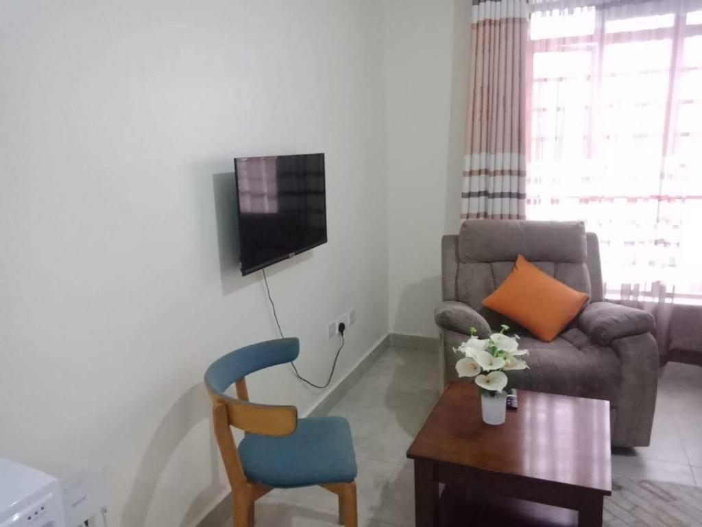 a living room with a couch and a chair and a table at Eden's Studio apartment in Syokimau